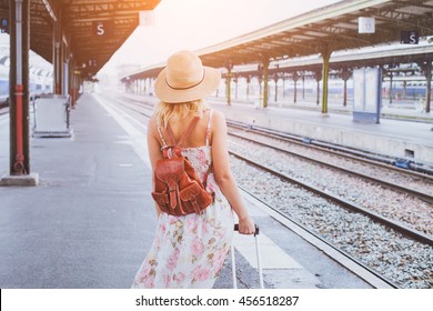 summer travel, woman with suitcase waiting for  her train on platform of railway station