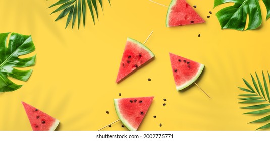 Summer trendy bright watermelon pattern layout. Red watermelon slices, tropical leaves, monstera plants and leaf shadows on yellow background, flat lay, top view - Powered by Shutterstock