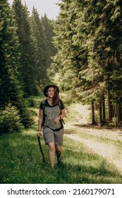 Summer trip to the mountains. A woman walks in the forest in summer. Hiking in the mountains. Active holiday in summer. Walk along the forest road. - Shutterstock ID 2160179071