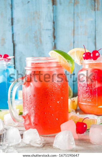 Summer tropical cold drinks. Blue Hawaiian, Tequila\
sunrise, Sea breeze cocktails over light blue wooden beach\
background, copy space