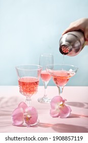 Summer Tropical Pink Cocktail Wine Champagne In A Different Glasses Decorated Pink Orchid Flowers. Human Hand Pouring From Shaker Cocktail