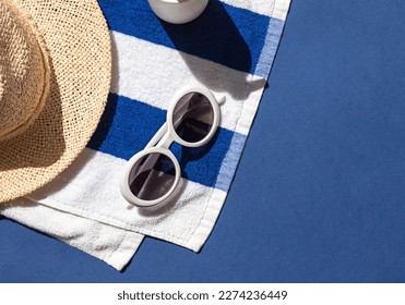 Summer vacation beach concept frame with retro sunglasses, striped towel and straw hat on the blue background. Copy space - Powered by Shutterstock