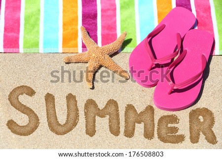 Summer vacation beach travel text concept. SUMMER written in sand with water next to beach towel, summer sandals and starfish.