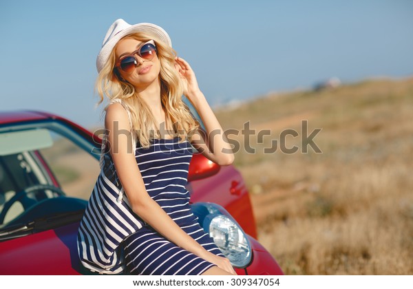 Summer vacation. Car trip. Travelling. Car travel. By
the sea. Beautiful blonde woman standing with red small car on the
background. Sea style. Summer vacation car road trip freedom
concept. 