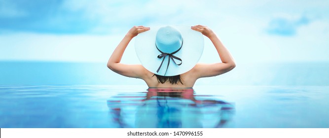 Summer vacation concept, Asian woman with white hat relax in infinity pool hotel resort with sea beach background at Chanthaburi, Thailand