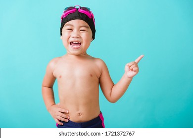 Summer Vacation Concept, Closeup Portrait Asian Happy Cute Little Child Boy Wear Goggles And Swimsuit, Kid Having Fun With In Summer Vacation Point To Side Away, Studio Shot Isolated Blue Background