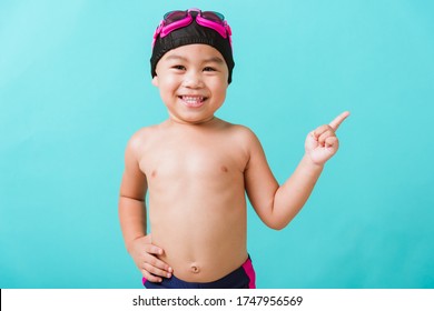 Summer Vacation Concept, Closeup Portrait Asian Happy Cute Little Child Boy Wear Goggles And Swimsuit, Kid Having Fun With In Summer Vacation Point To Side Away, Studio Shot Isolated Blue Background