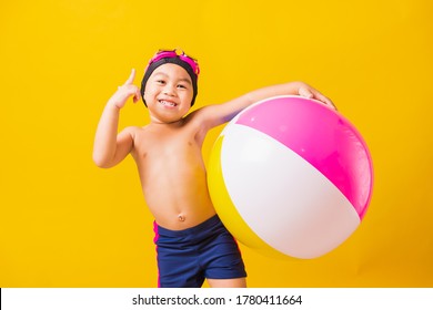 Summer Vacation Concept, Portrait Asian Happy Cute Little Child Boy Smiling In Swimsuit Hold Beach Ball, Kid Having Fun With Inflatable Ball In Summer Vacation, Studio Shot Isolated Yellow Background