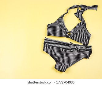 Summer Vacation Concept. Top View, Flat Lay, Copy Space.Black And White Stripe Pattern  Bikini Swim Suit  On L Yellow Background. Female Sexy Swimwear.