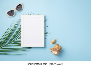 Summer Vacation Concept. Top View Photo Of White Photo Frame Sunglasses Shells And Palm Leaves On Isolated Pastel Blue Background With Empty Space