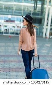 Summer Vacation Concept. Woman Carrying Suitcase And Walking To Airport Terminal, View From The Back