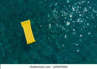 Summer Vacation Concept. Yellow Inflatable Mattress In Blue Azure Sea Water. Overhead View