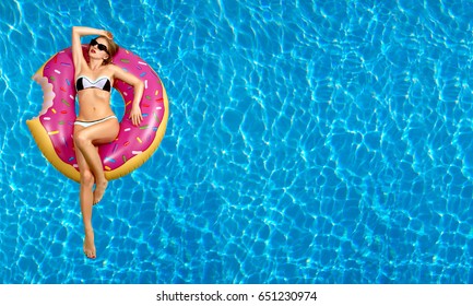 Summer Vacation. Enjoying suntan Woman in bikini on the inflatable mattress in the swimming pool. 