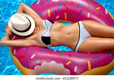 Summer Vacation. Enjoying suntan Woman in bikini on the inflatable mattress in the swimming pool. 