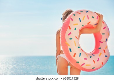 Summer Vacation. Enjoying suntan woman in white bikini with donut mattress near the swimming pool.