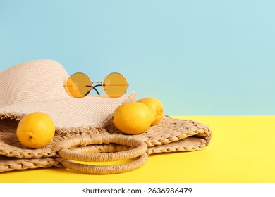Summer vacation essentials: straw hat, round sunglasses, woven bag, and fresh lemons on a bright background