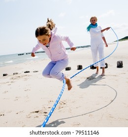 Summer vacation - family playing with skipping rope on the beach