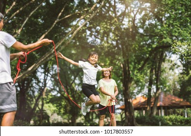 Summer vacation - happy family playing with skipping rope at green nature park