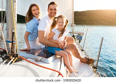 Summer Vacation. Happy Family Posing Sitting On Yacht Smiling To Camera Enjoying Sea Trip On Sailboat Outdoors. Parents And Daughter Sailing On Boat Spending Summer Day In Sea