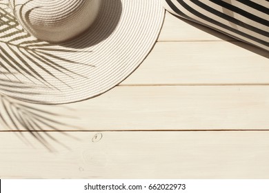 Summer Vacation, Holiday, Travel, Tourism Concept. Sun Straw Hat, Striped Bag And Shadow Of Tropical Palm Leaves On White Wooden Background. Top View With Space For Text. 