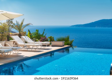 Summer vacation at poolside. Veranda decorated with deck chairs and umbrella with an ocean view