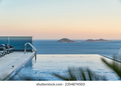 Summer vacation at poolside. Veranda decorated with deck chairs and umbrella with an ocean view - Powered by Shutterstock