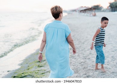 Summer Vacation At Sea. Boy And Senior Woman At Seaside. Grandmother With Grandchild Are Resting On Sea, Running On Beach Having Fun At Summer Holiday. Active Parents, People Activity With Children.