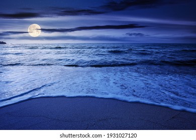 summer vacation at the seaside at night. beautiful seascape in full moon light. calm waves wash the golden sandy beach. fluffy clouds on the sky