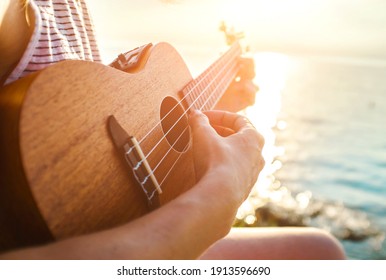 Summer Vacation. Smellingcaucasian women relaxing and playing on ukulele on beach, so happy and luxury in holiday summer, outdoors sunset sky background. Travel and lifestyle Concept.