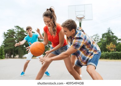 summer vacation, sport, games and friendship concept - group of happy teenagers playing basketball outdoors - Powered by Shutterstock