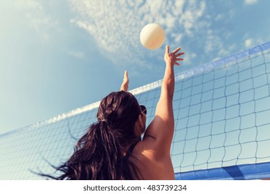summer vacation, sport, leisure and people concept - young woman playing volleyball on beach and catching ball