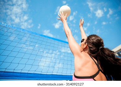 summer vacation, sport and people concept - young woman with ball playing volleyball on beach