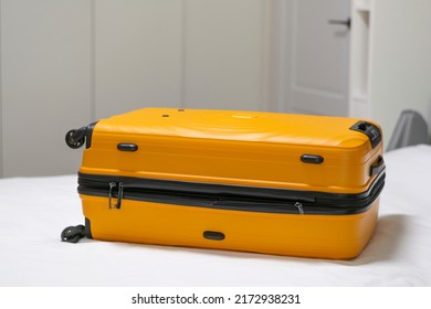 Summer Vacation Suitcase For Home Bed Or Hotel Room No People.Orange Plastic Suitcase On Wheels. Concept: Travel, Tourism, Clothing Accessories, Orange Plastic 