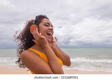 Summer Vacation, Technology And Internet Concept. Afro Woman Listening To Music With Headphone On The Beach