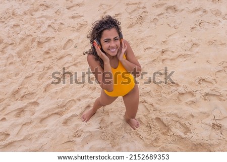 summer vacation, technology and internet concept. afro woman listening to music with headphone on the beach