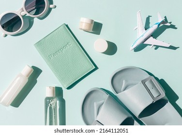Summer vacation travel concept composition with airplane, cosmetics, passport and flip flops on the bright sunny blue background.  - Shutterstock ID 2164112051