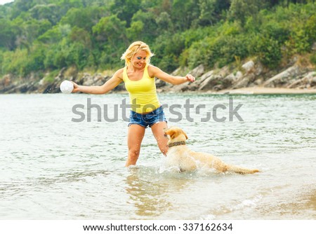 Summer vacation - woman with dog playing on the beach