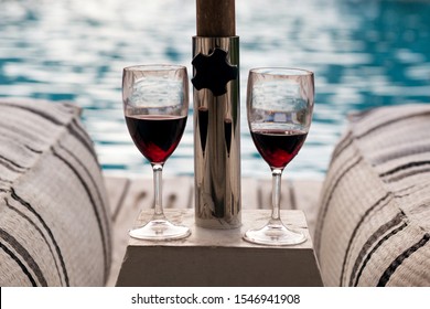 Summer vacations concept image. Two glass of red wine outdoors in a pool side terrace in a sunny summer evening. Wineglasses place by the swimming pool. - Powered by Shutterstock