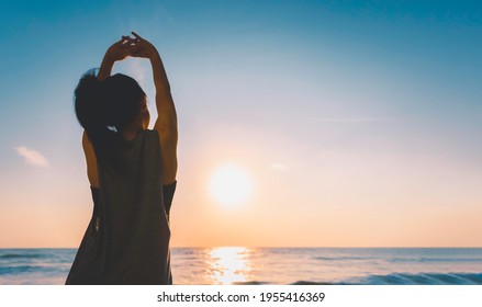 Summer vacations freedom concept, Silhouette Healthy sporty female stretch arm doing exercise on the beach at sunrise or sunset time