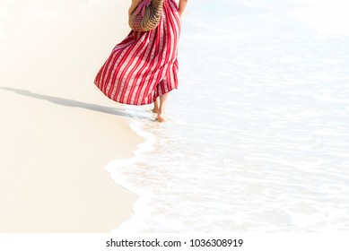 Summer Vacations. Smiling woman wearing fashion summer walking on the sandy ocean beach. Happy woman enjoy and relax vacation. Lifestyle and Travel Concept