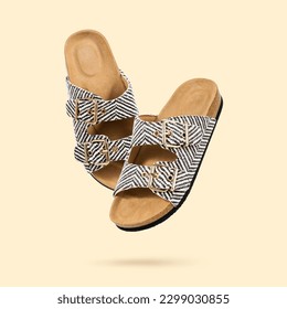 Summer Vegan cork sandals with double straps flying on a beige background. Fashionable female trendy slippers. Eco-friendly natural shoes. Cut out objects for design, Creative concept. Copy space.