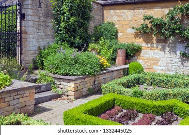 Summer Vegetable And Herb Garden With Lettuce Growing In Plots Enclosed By Trimmed Hedge, Herbs And Fruit Trees By The Stone Wall .