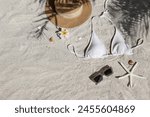 Summer vibes. Straw hat, bathing suit and sunglasses on a sandy beach.. Flat lay, copy space, top view, background.