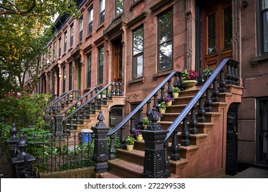  Sommerblick auf eine Reihe von Geschäften und historischen, braunen Gebäuden auf einer der ikonischen Straßen in einem Viertel von Brooklyn in New York City.