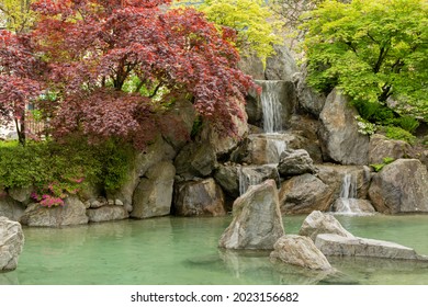 Summer views of the little Japanese garden at Interlaken with colorful trees, a pool with rocks and a small manmade waterfalls in the back at Interlaken in Switzerland.