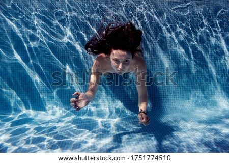 Summer wanderlust of a woman dive and swimming in the pool, woman  under the water enjoying the pool at summer. The woman has long hair and is diving in a pool