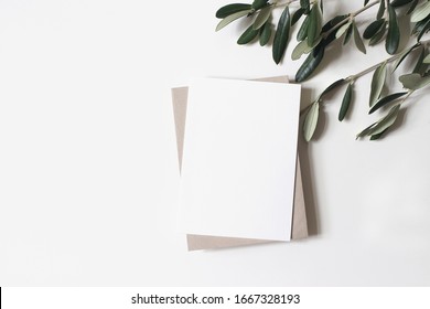 Summer Wedding Stationery Mock-up Scene. Blank Vertical Greeting Card, Craft Paper Envelope And Olive Branches Isolated On White Table Background. Feminine Mediterranean Flat Lay, Top View.