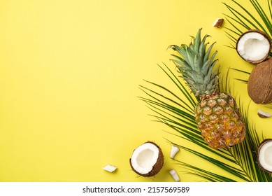 Summer weekend concept. Top view photo of fresh tropical fruits coconuts pineapple and palm leaves on isolated yellow background with copyspace