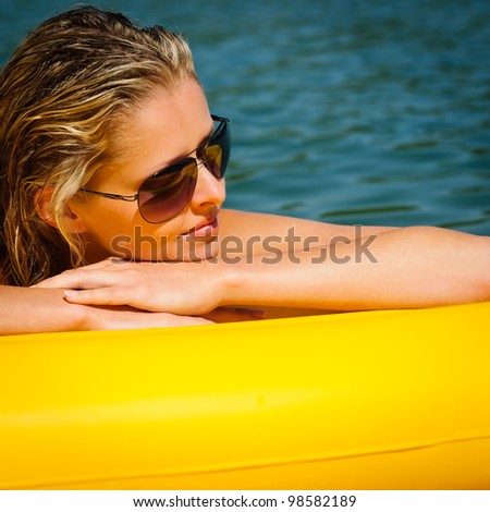 Summer woman daydreaming lying on yellow floating mattress close-up