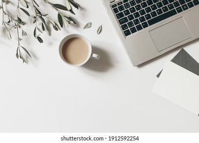 Summer workspace composition. Blank greeting card mock-up scene. Cup of coffee, olive tree branches and laptop isolated on white table background. Flat lay, top view. Blogger design. Home office. - Powered by Shutterstock
